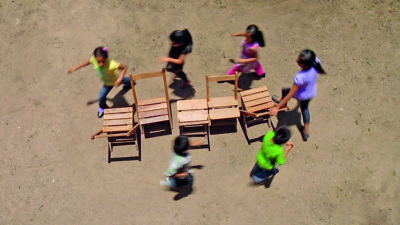 Children playing musical chairs on the beach by Francis Alÿs